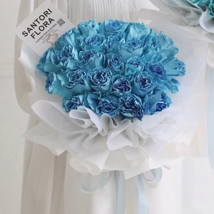 Blue rose bouquet wrapped in layered white wavy paper with a decorative light blue ribbon