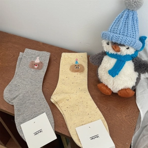 Detailed macro view of gray and beige cotton socks featuring cute 3D cartoon bear accents