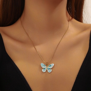 Golden stainless steel necklace with blue gradient butterfly pendant worn by a model