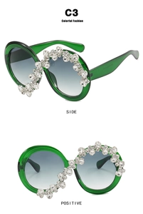 Detailed view of oversized green frame sunglasses with sparkling rhinestone embellishments