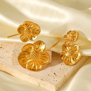 Elegant 18K gold-plated stainless steel flower jewelry set on organic stone and silk background