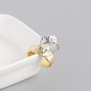 Macro shot of silver and gold rings with molten lava texture on white ceramic edge