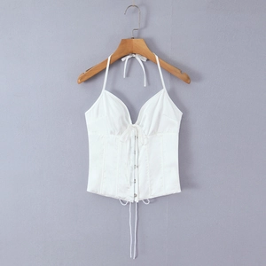 Primer plano del top blanco con cuello halter, escote en V y detalle de cordones