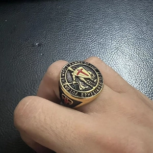 Close-up of gold men's shield ring with red cross and religious engraved scripture
