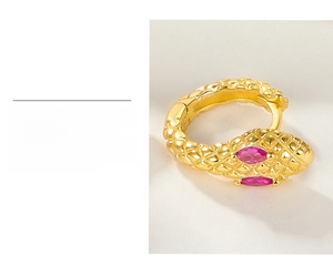 Macro shot of gold plated snake earrings featuring pink zircon eyes and scales