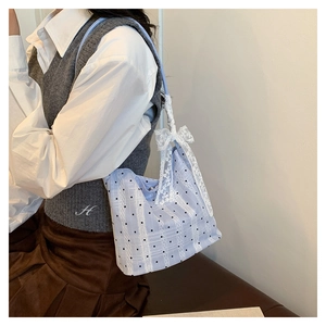 Light blue bucket bag with black polka dots and decorative white lace bow on the shoulder strap