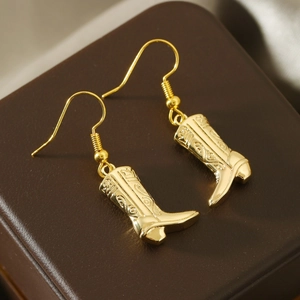 Macro shot of gold cowboy boot earrings with intricate floral relief details