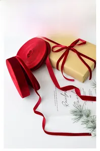 Detail of premium red velvet ribbon on gift box with festive pine branches and natural light