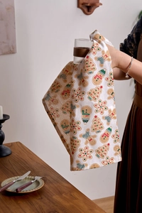 Detail der Weihnachtsserviette mit Lebkuchen- und Schneemannmuster auf beigem Stoff
