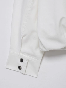 Detailed close-up of white linen bomber jacket sleeve with dual metal snap button closure