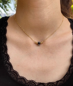 Close-up of gold layered necklace with evil eye pendant on a female model