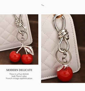 Detail of red cherry and apple resin pendants with polished silver metal clasps on a bag