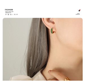 Close-up of 18K gold plated hoop earring with inlaid green zircon on model's ear