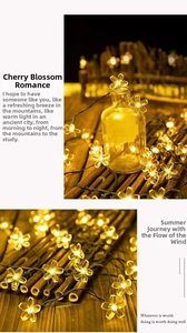 Close-up of warm yellow LED cherry blossom fairy lights wrapped around a glass bottle