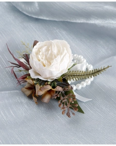 Detailed shot of a white artificial flower wrist corsage with pearls and vintage leaves