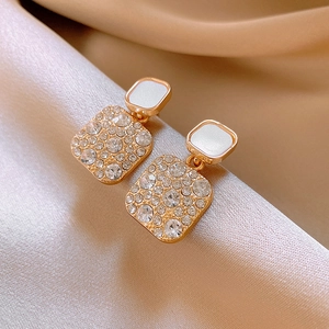 Detail of gold geometric earrings with square shells and pavé crystal embellishments