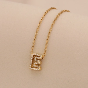 Macro view of a gold-plated letter E pendant necklace with clear sparkling rhinestones