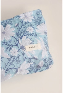 Dettaglio macro del tessuto jacquard blu e dell'etichetta H&R BAG su una trousse trucco