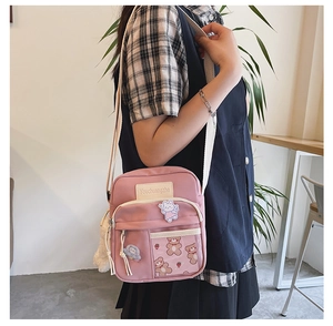 Détail du sac bandoulière en toile rose avec écussons mignons et sangle réglable