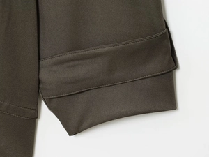Detaillierte Nahaufnahme der dunkelbraunen Twill-Stoffstruktur an Ärmelbund und Saum