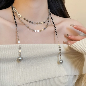 Detail of layered necklace with black beads, silver discs, and grey faux pearl pendants