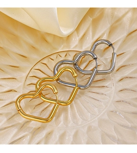 Détail de créoles en forme de cœur dorées et argentées sur un plateau en verre
