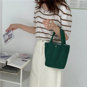 Close-up of green houndstooth wool tote bag featuring a gold snap button and fabric handle