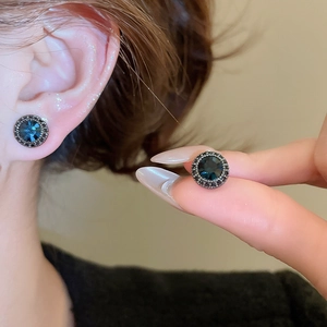 Macro shot of vintage round blue zircon earrings with dark gunmetal micro-pave setting