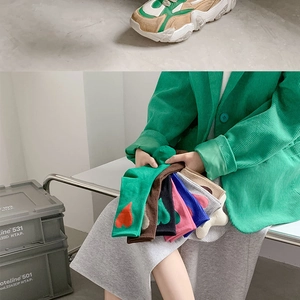 Detail of colorful mid-calf socks with heart pattern held by a model in a green jacket
