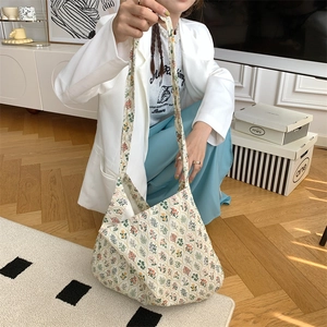 Floral canvas shoulder bag held by a model in a cozy indoor lifestyle setting