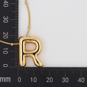 Detail view of gold puffy 3D balloon letter R pendant necklace with measurement scale