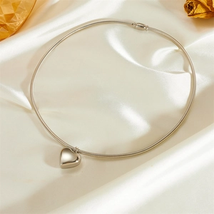 Detail of silver snake chain necklace with a 3D polished heart pendant on satin fabric