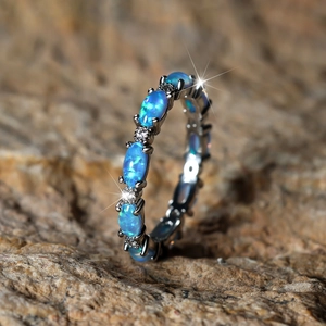 Macro detail of eternity ring featuring oval blue opals and sparkling diamonds on stone