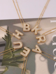 Macro display of gold bubble letter necklaces with sparkling zircon pavé pendants