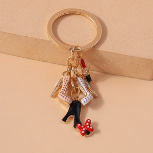 Fashionable golden keychain featuring enamel high heels, lipstick, and a polka dot bow charm