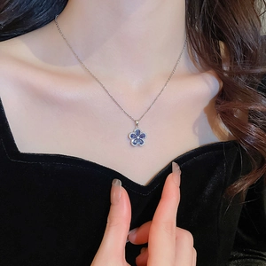 Detailed close-up of blue flower pendant necklace worn on neck with velvet clothing