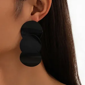 Minimalist geometric triple disc drop earrings in matte black on a side-view model