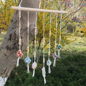 Detailed handmade woven wall hanging with natural crystals and fringes on a wooden rod