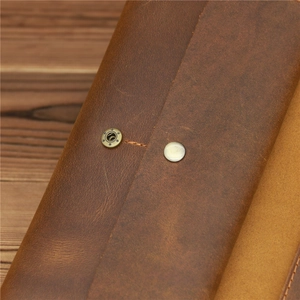 Macro shot of crazy horse leather texture with vintage metal snap button and stitching