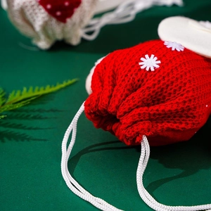Close-up of red knitted Christmas gift bag with white snowflake appliques and drawstring