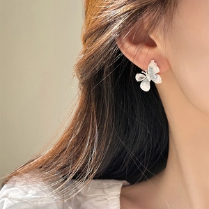 Détail d'une boucle d'oreille papillon argentée portée par un mannequin de mode