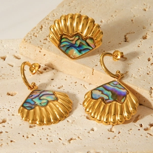 Detailed view of gold shell earrings and ring set with abalone shell inlay on stone