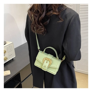 Detail view of mint green handbag with baroque gold buckle shown on a model