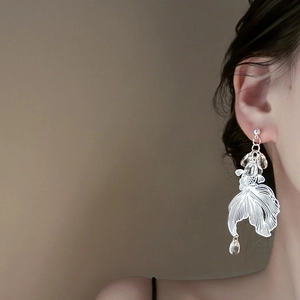 Silver koi fish drop earrings with hollow metal design and clear bead charms on model