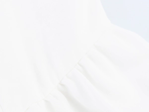 Close-up of white cotton fabric texture and gathered seam detailing on a maxi dress