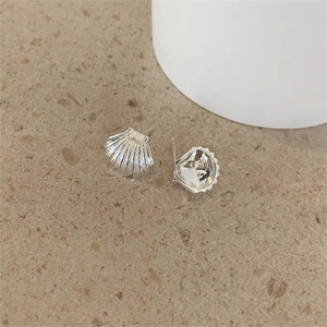 Macro shot of silver shell-shaped stud earrings with fine radial stripes on stone