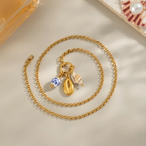 Detail view of gold chain necklace featuring blue and white porcelain bead and sea shell