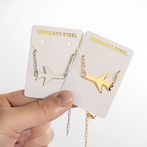 Minimalist gold and silver stainless steel airplane pendants on jewelry display cards