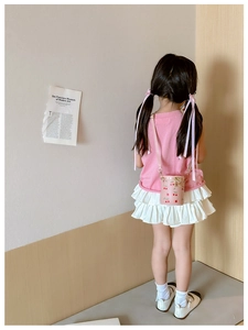 Little girl wearing a pink cherry print bucket bag with adjustable crossbody strap