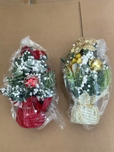 Detail of two mini 20cm Christmas trees in red and gold themes with plastic packaging